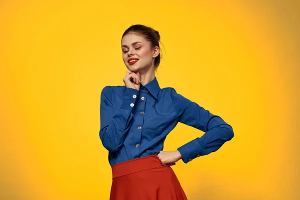 Atractiva mujer de camisa azul haciendo gestos con sus manos y falda roja fondo amarillo retrato recortado vista — Foto de Stock