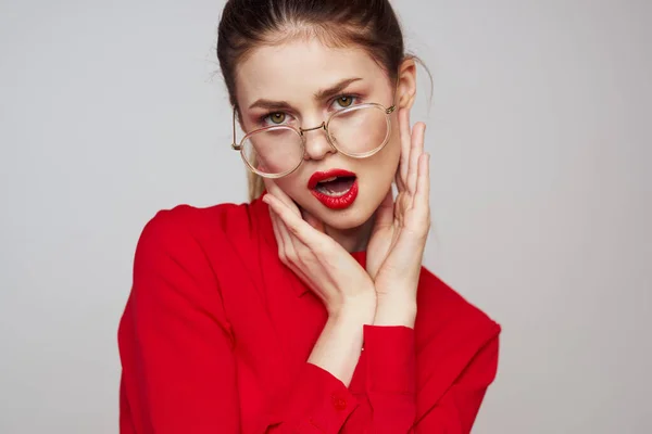 Fashionabla kvinna i en röd skjorta på en ljus bakgrund roliga känslor ljusa makeup glasögon attraktivt utseende — Stockfoto