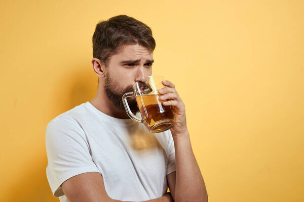 Man with a mug of beer fun alcohol lifestyle white t-shirt yellow isolated background
