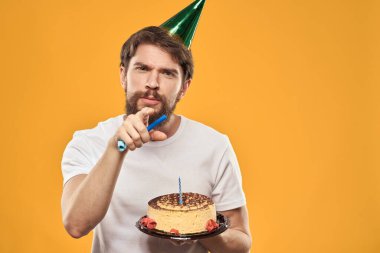 Pastalı sakallı ve şapkalı bir adam doğum gününü kutluyor.