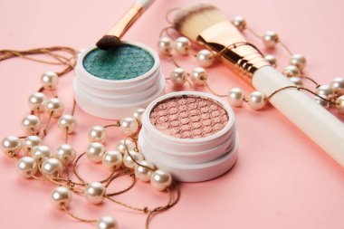 Göz falı aksesuarlar, boncuklar makyaj fırçaları pembe arka planda profesyonel kozmetik ürünleri koleksiyonu.