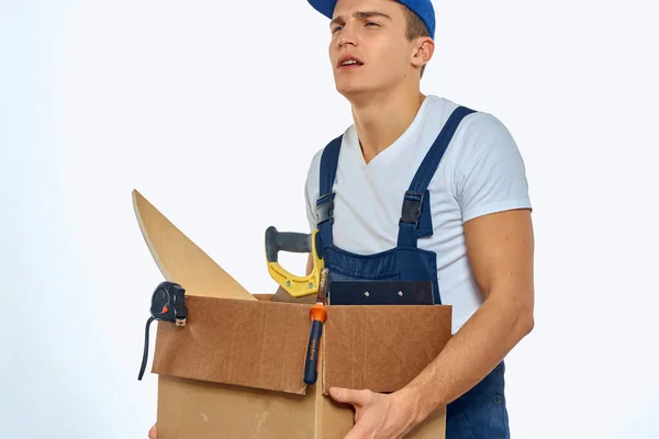 Ένας άνδρας με στολή εργασίας με ένα κουτί στο χέρι να φορτώνει μια υπηρεσία παράδοσης. — Φωτογραφία Αρχείου
