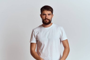 Beyaz tişörtlü kaslı bir adam açık arkaplan görünümlü.