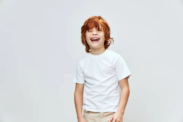 Porträtt av glad rödhårig pojke i vit t-shirt ler brett beskuren visa studio — Stockfoto
