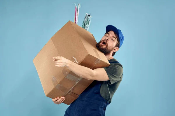 Posta arabasının mavi arka planında kutuları olan işçi üniformalı bir adam. — Stok fotoğraf