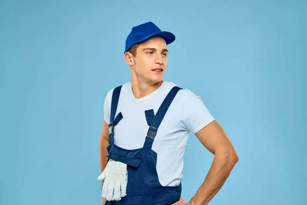 Working man in uniform of gloves loader rendering service blue background — Stock Photo, Image