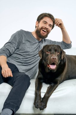 Beyaz bir kanepede siyah köpeği olan bir adam. Arka planda, yakın planda kesilen evcil hayvan insan arkadaş duyguları. Eğlenceli.