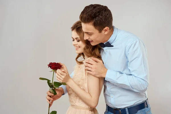 Milenci muži a žena objetí romantika láska červená růže světlo pozadí — Stock fotografie