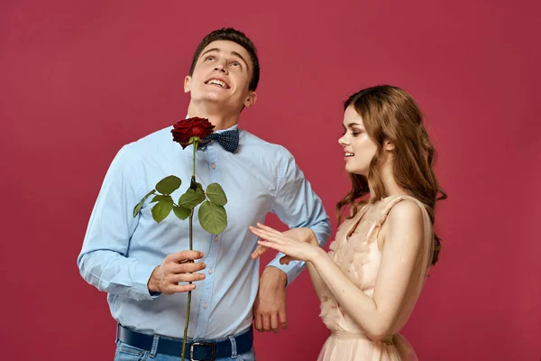 Enamored man and woman with a red flower on a pink background hug each other Copy Space — Stock Photo, Image