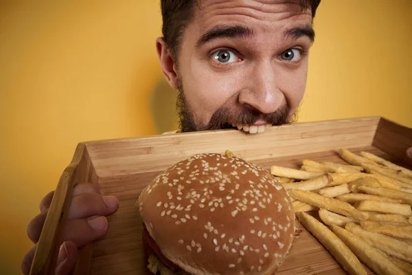 Man met houten pallet fast food hamburger frites dieet voedselinname close-up — Stockfoto