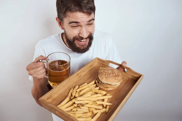 Mann mit hölzernem Tablett Bierkrug Pommes und Hamburger Fast Food Kalorien Modell weißes T-Shirt — Stockfoto