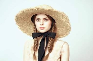 Bej elbiseli, hasır şapkalı, siyah kurdele takmış, manken görünümlü romantik bir kız.