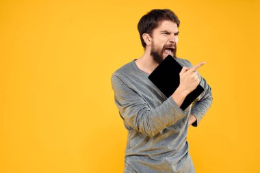 Elinde tablet olan sakallı adam teknolojiyle kablosuz cihaz sarısı arka planda çalışıyor.