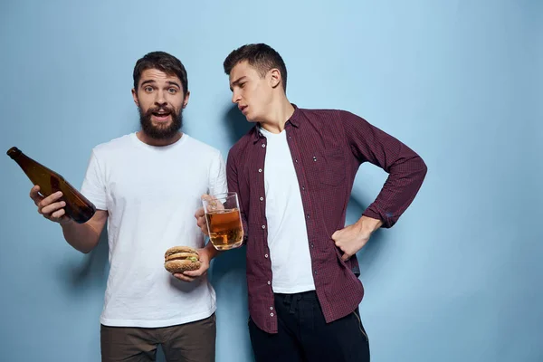 Deux amis ivres joyeux buvant de la bière mode de vie émotions sur un fond bleu — Photo