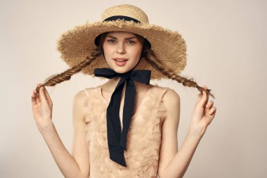 Bej elbiseli, hasır şapkalı, siyah kurdele takmış, manken görünümlü romantik bir kız.