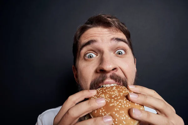 Homem comendo hambúrguer fast food restaurante Gourmet comendo fundo escuro — Fotografia de Stock