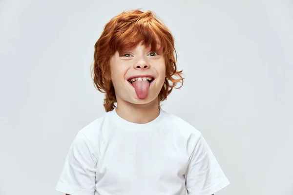 Κοκκινομάλλης αγόρι δείχνει γλώσσα περικοπή άποψη του λευκού t-shirt διασκέδαση — Φωτογραφία Αρχείου