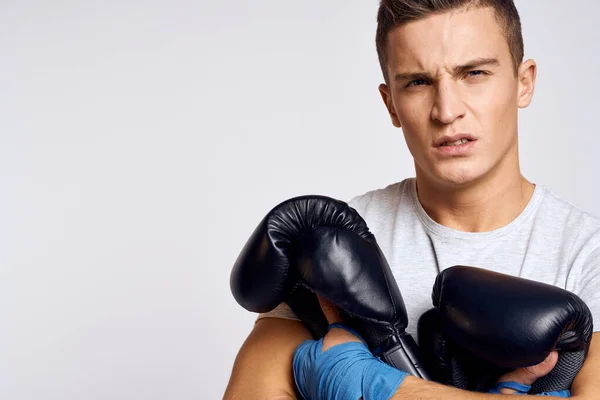 Hombre fuerte con guantes de boxeo y en una camiseta blanca sobre un fondo aislado recortado vista del modelo — Foto de Stock