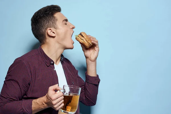 Veselý opilý muž s pivem hrnek a hamburger v ruce dieta jídlo životní styl modré pozadí — Stock fotografie