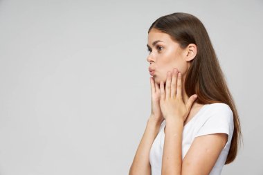 Kadın el ele tutuşup beyaz tişörtün arka planına bakıyor. 