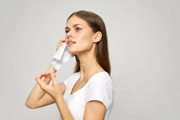 Retrato de una mujer se pone una máscara médica en la cara camiseta blanca — Foto de Stock