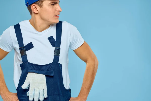 Hombre trabajador en uniforme de guantes cargador prestación de servicio fondo azul — Foto de Stock