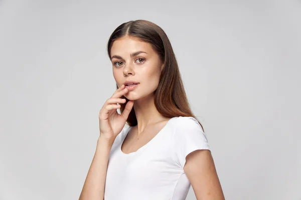Pretty woman in a white T-shirt holds her hand near her face — Stock Photo, Image