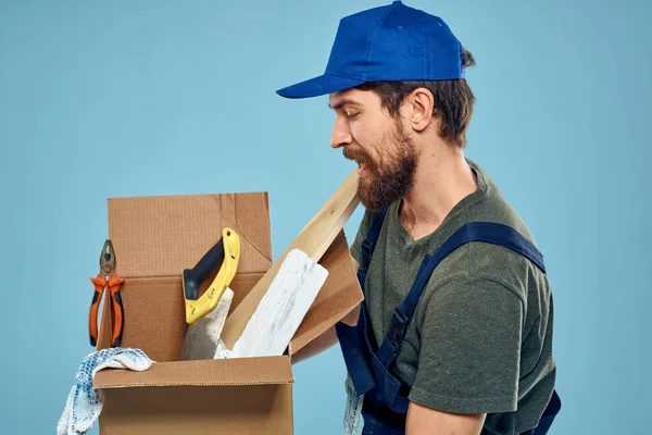 Trabalhador homem em caixa uniforme ferramentas construção azul fundo — Fotografia de Stock