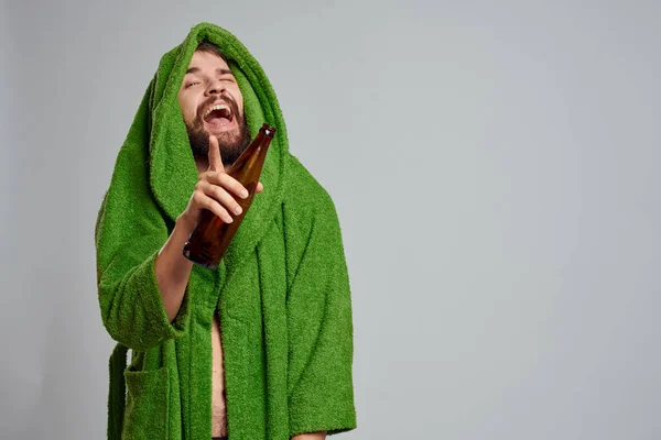 Homem bêbado com garrafa de álcool na mão e roupão verde bebendo relaxamento — Fotografia de Stock