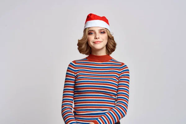 Счастливая женщина в рождественской шапочке и в полосатом свитере жестикулирует руками на новогодние праздники — стоковое фото