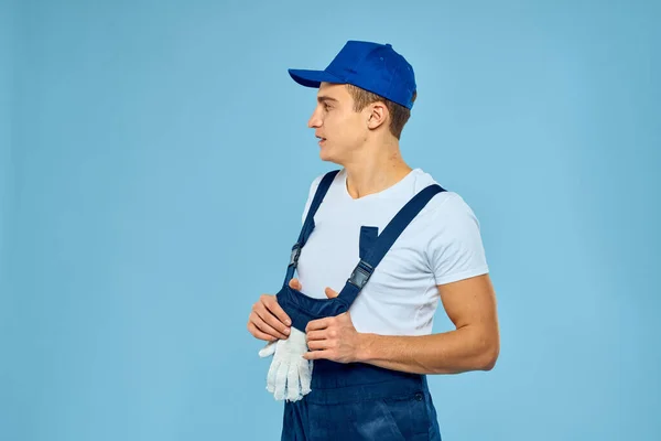 Trabalhador em uniforme de luvas carregador prestando serviço de fundo azul — Fotografia de Stock