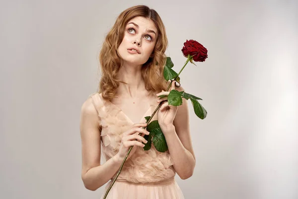 Ritratto di una bella donna con una rosa rossa su sfondo beige vista ritagliata di un abito da sera — Foto Stock