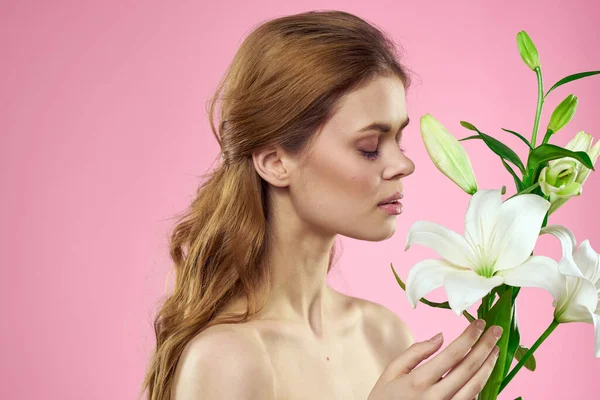 Mulher bonita segurando buquê de flores em mãos ombros nus fundo rosa charme — Fotografia de Stock