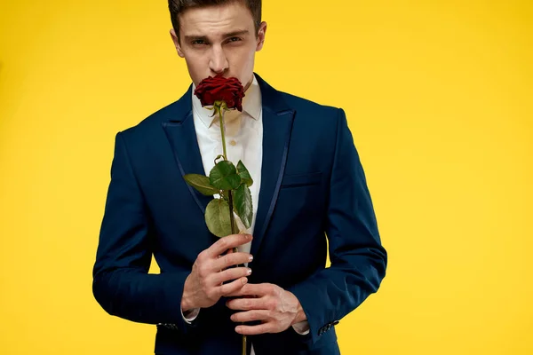若いです男でA古典的なスーツとともに赤いバラで彼の手に上の黄色の背景感情クリップビューモデル — ストック写真