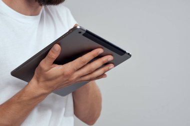 Açık arkaplanda dokunmatik ekranlı tablet erkek elleri beyaz tişört kırpılmış görünüm