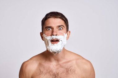 Yüzünde beyaz tıraş köpüğü olan yakışıklı bir adam ve jilet gibi omuzları olan temiz bir cilt.