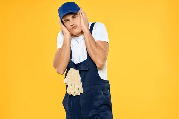 Travailleur en uniforme de gants rendant service fond jaune — Photo