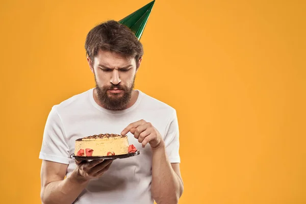 ケーキと誕生日を祝う帽子をかぶった髭の男 — ストック写真