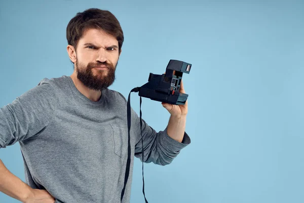 Hombre fotógrafo con una cámara profesional en sus manos cerca de la cara de un hobby enfoque creativo fondo azul — Foto de Stock