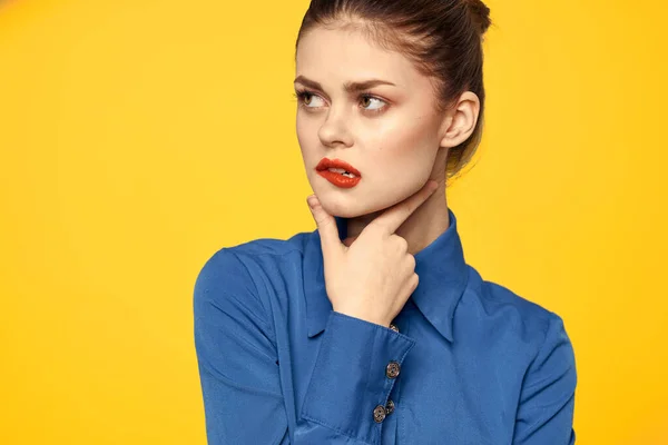 Retrato de uma mulher em uma camisa azul com maquiagem brilhante lábios vermelhos fundo amarelo vista recortada — Fotografia de Stock