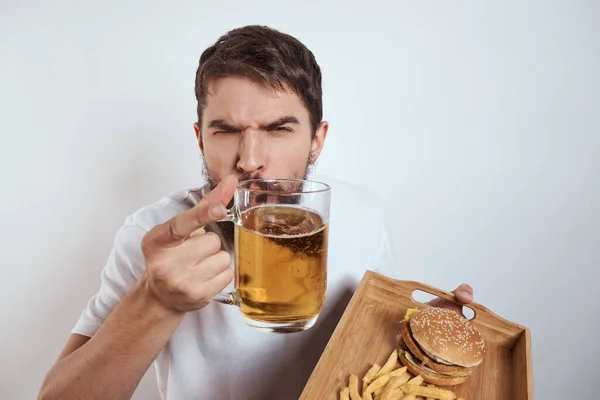 Homme avec plateau en bois tasse de bière frites et hamburger fast food calories modèle t-shirt blanc — Photo