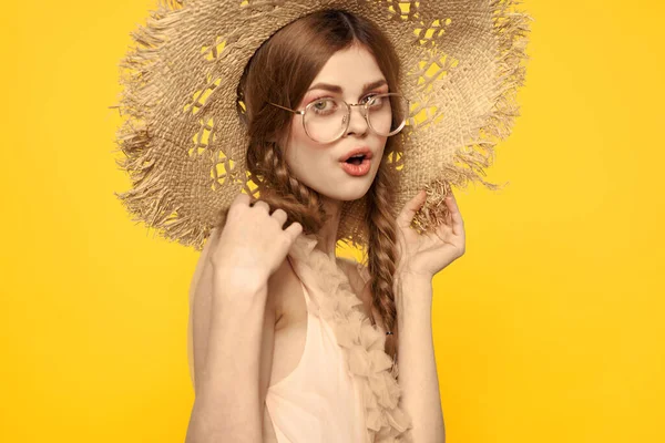 Saçları örgülü ve sarı arka planda şapkası olan güzel bir kadının portresi. — Stok fotoğraf