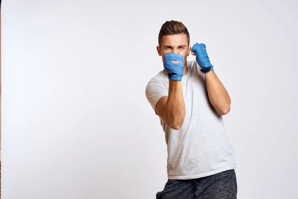 Esportivo boxeador masculino em luvas azuis praticando socos em um fundo leve vista cortada — Fotografia de Stock