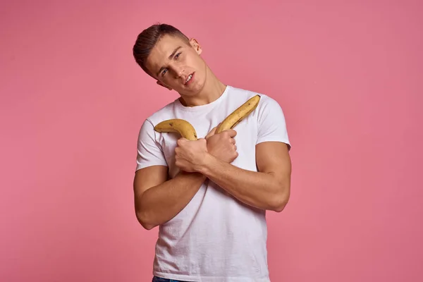 Uomo con frutta in mano su uno sfondo rosa cibo sano vitamine rosa sfondo bianco t-shirt modello — Foto Stock