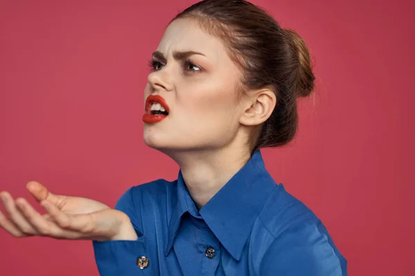 Donna energica con trucco luminoso e in una camicia blu su uno sfondo rosa gesti con le mani — Foto Stock