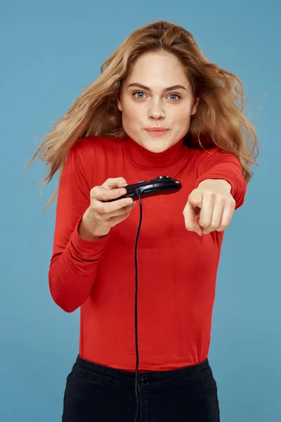 Bonita mujer gamepad en las manos jugando juegos de entretenimiento consolas de estilo de vida azul fondo chaqueta roja — Foto de Stock