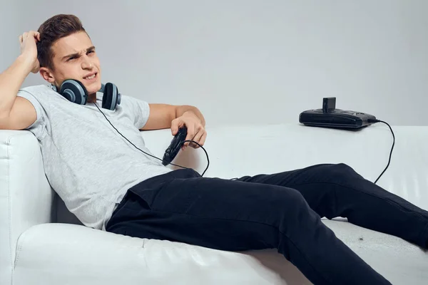 一名男子躺在沙发耳机、游戏平台、技术娱乐视频游戏平台上 — 图库照片