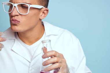 Elinde renkli sıvı kimya laboratuvarı modeli olan gözlüklü bir adam var.