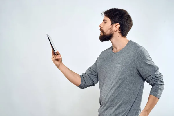 Ein Mann mit einem Tablet in der Hand Internet-Technologie Kommunikation graue Jacke heller Hintergrund — Stockfoto