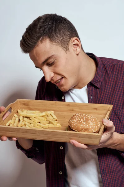 Man eating wooden pallet fast food french fries hamburger diet food restaurant light background — Stock Photo, Image